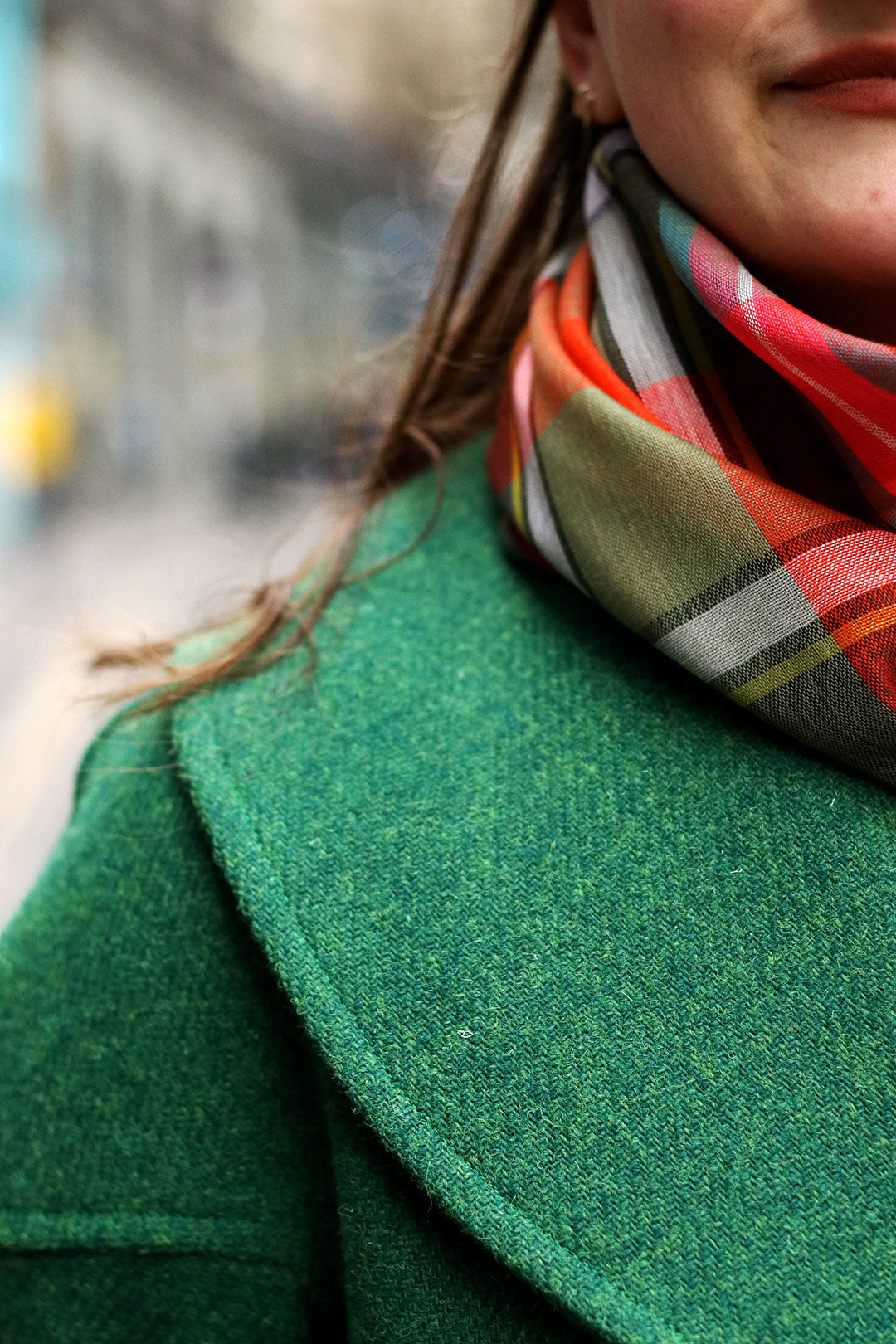 The classic Harris Tweed coat is made in a vibrant emerald green tweed with a royal blue satin lining, shown on model.