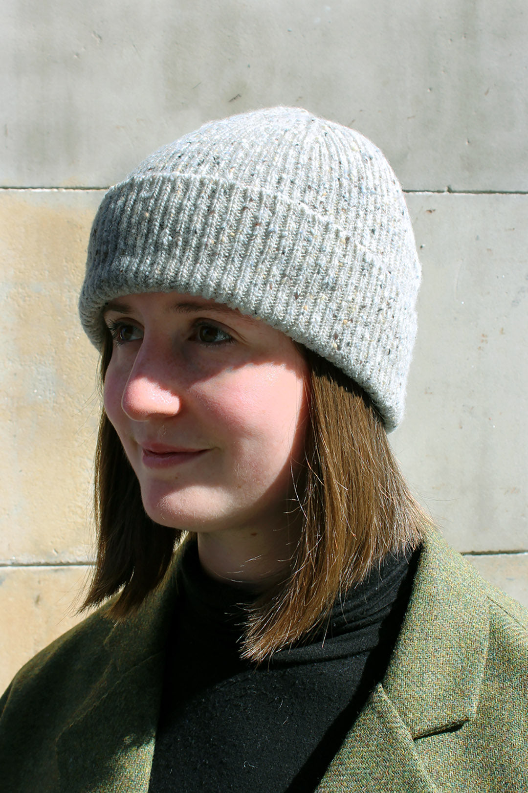 Knitted beanie hat in Donegal Yarn. Creamy grey yarn with flecks of brown, black and blue grey through it. Scottish Textiles Showcase.