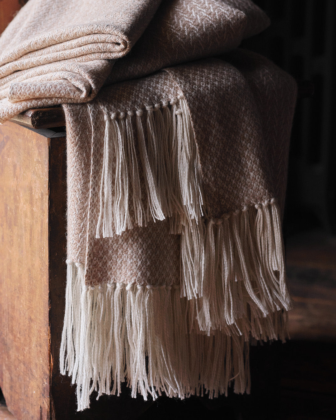 Araminta Campbell kingsize undyed alpaca throw in Woodland Inkcap pattern. Shown draped in rustic interior.