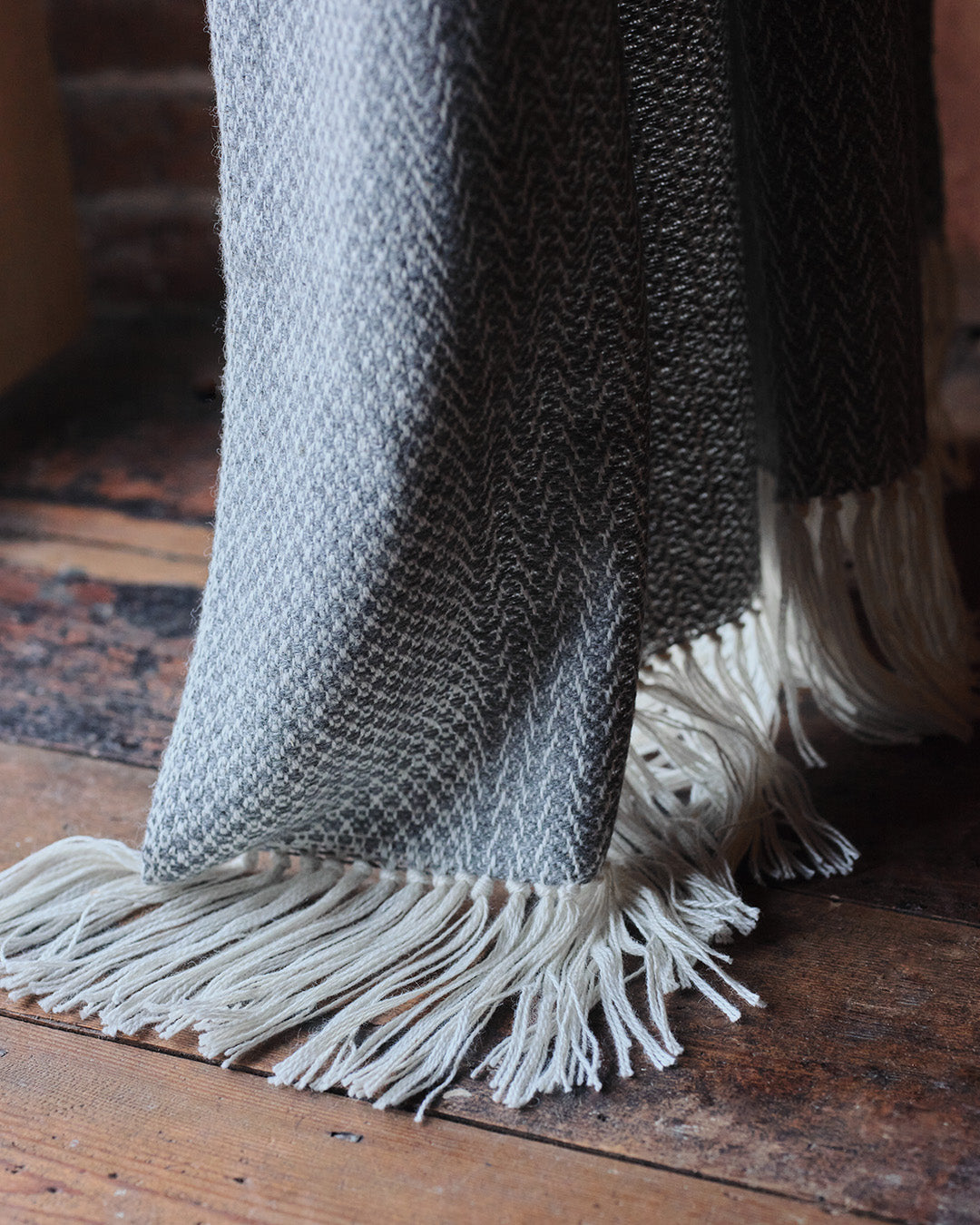 Araminta Campbell kingsize undyed alpaca throw in Woodland Inkcap pattern. Shown in rustic wooden interior.