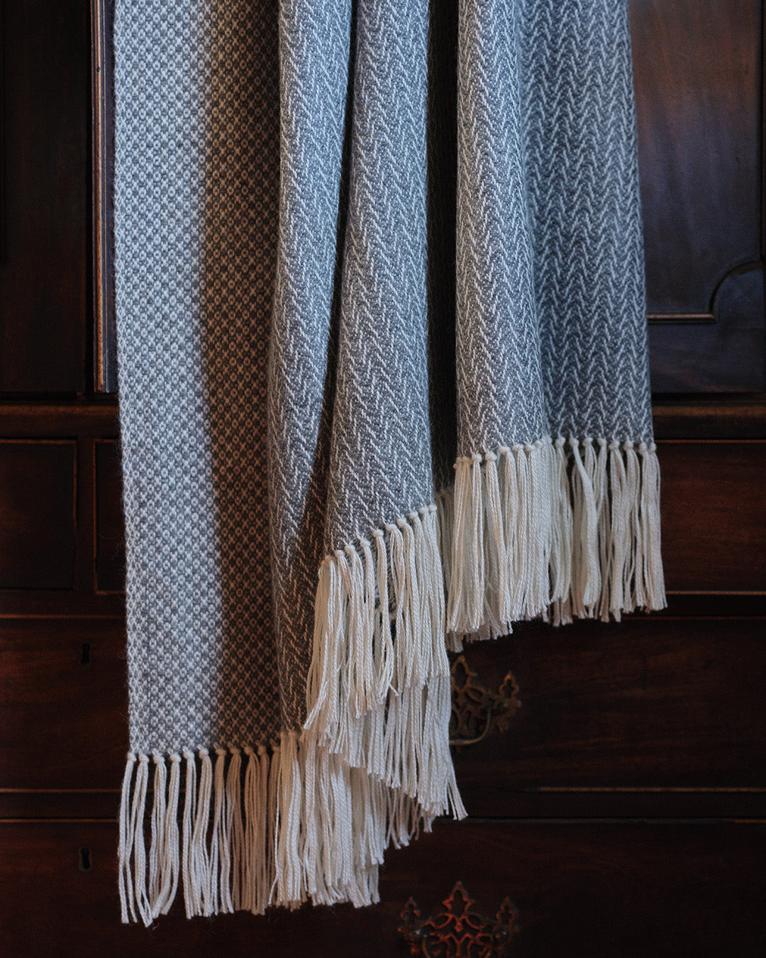 Araminta Campbell kingsize undyed alpaca throw in Woodland Inkcap pattern. Shown in dark wooden interior.