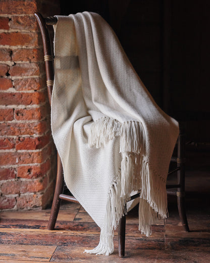 Araminta Campbell kingsize undyed alpaca throw in Woodland Inkcap pattern. Shown in rustic wooden interior.