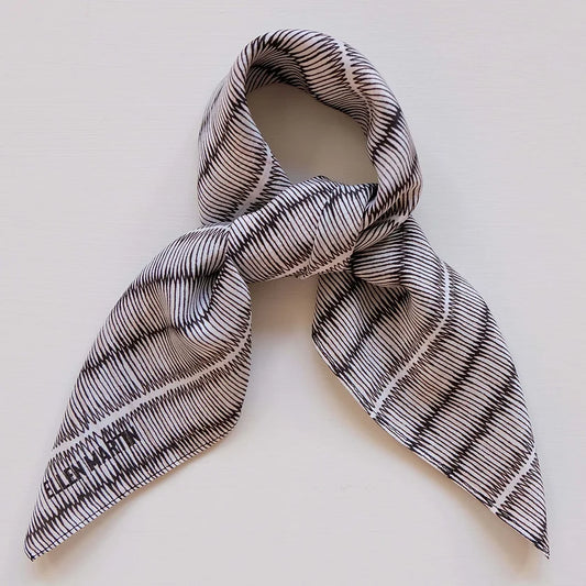 Black and white tatami print silk scarf, tied in knot on plain background.