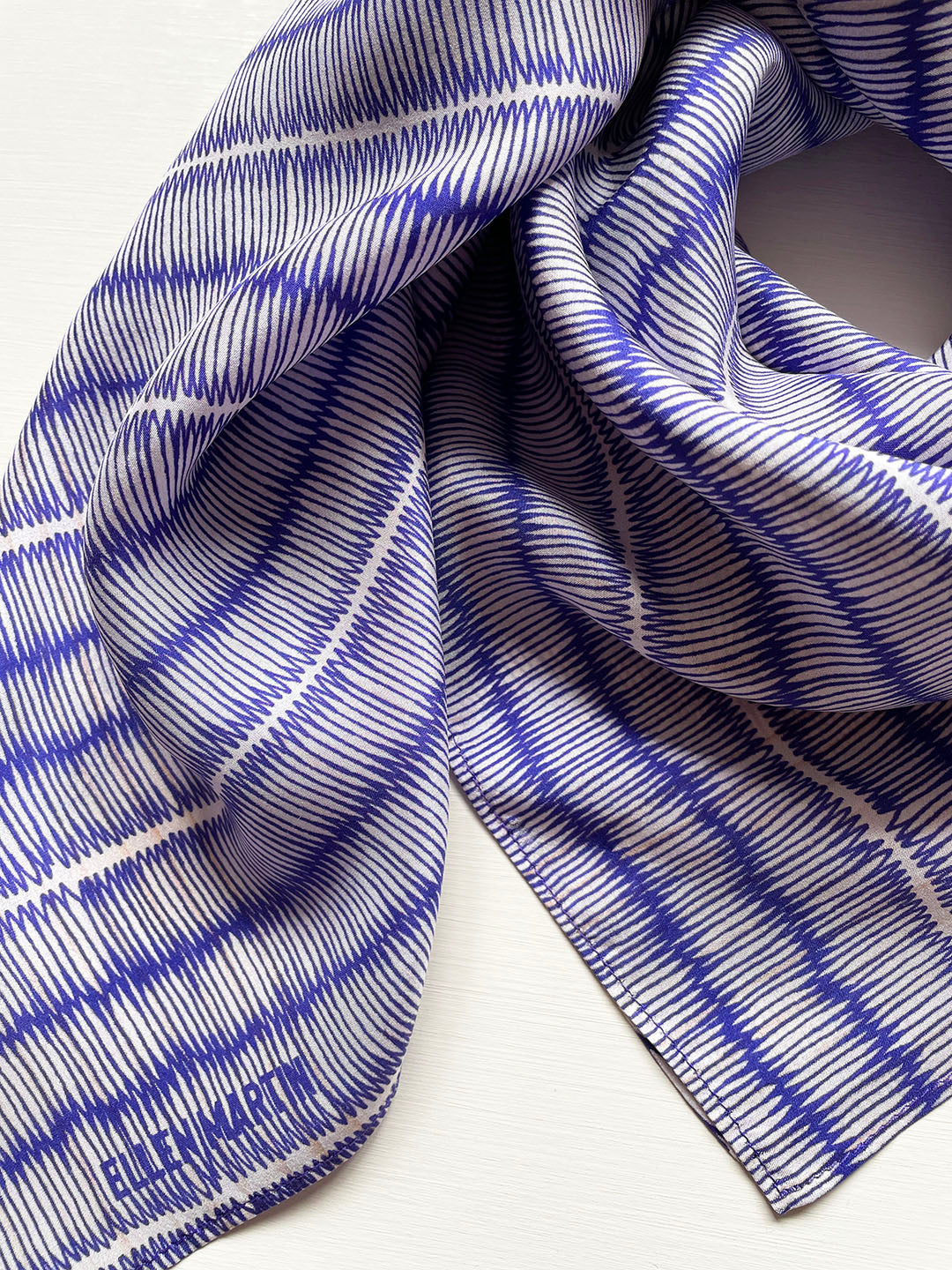 Blue and ivory large silk scarf with intricate hand-drawn print, shown draped on a plain background.
