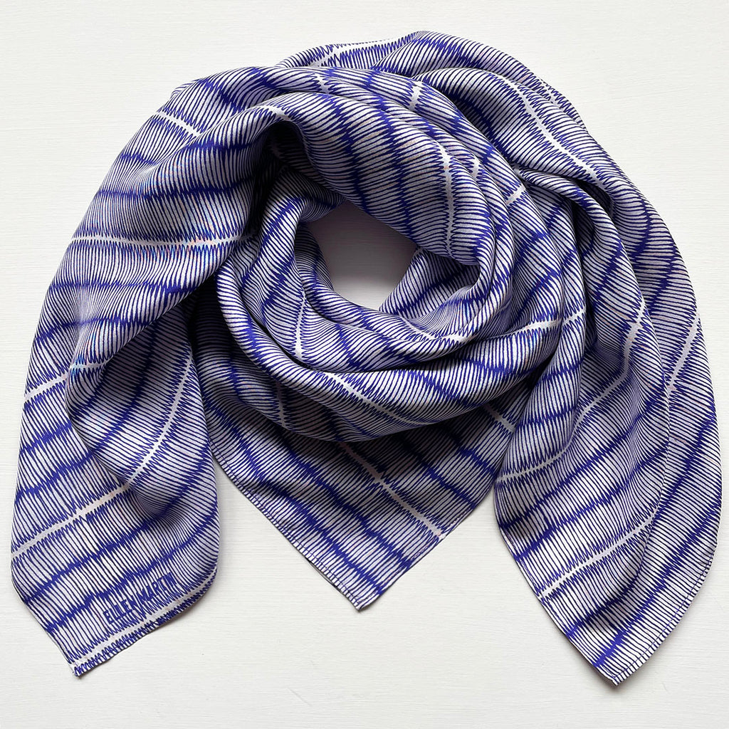 Blue and ivory large silk scarf with intricate hand-drawn print, shown draped on a plain background.