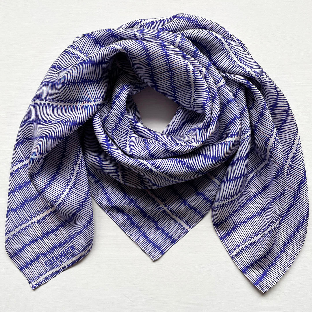 Blue and ivory large silk scarf with intricate hand-drawn print, shown draped on a plain background.