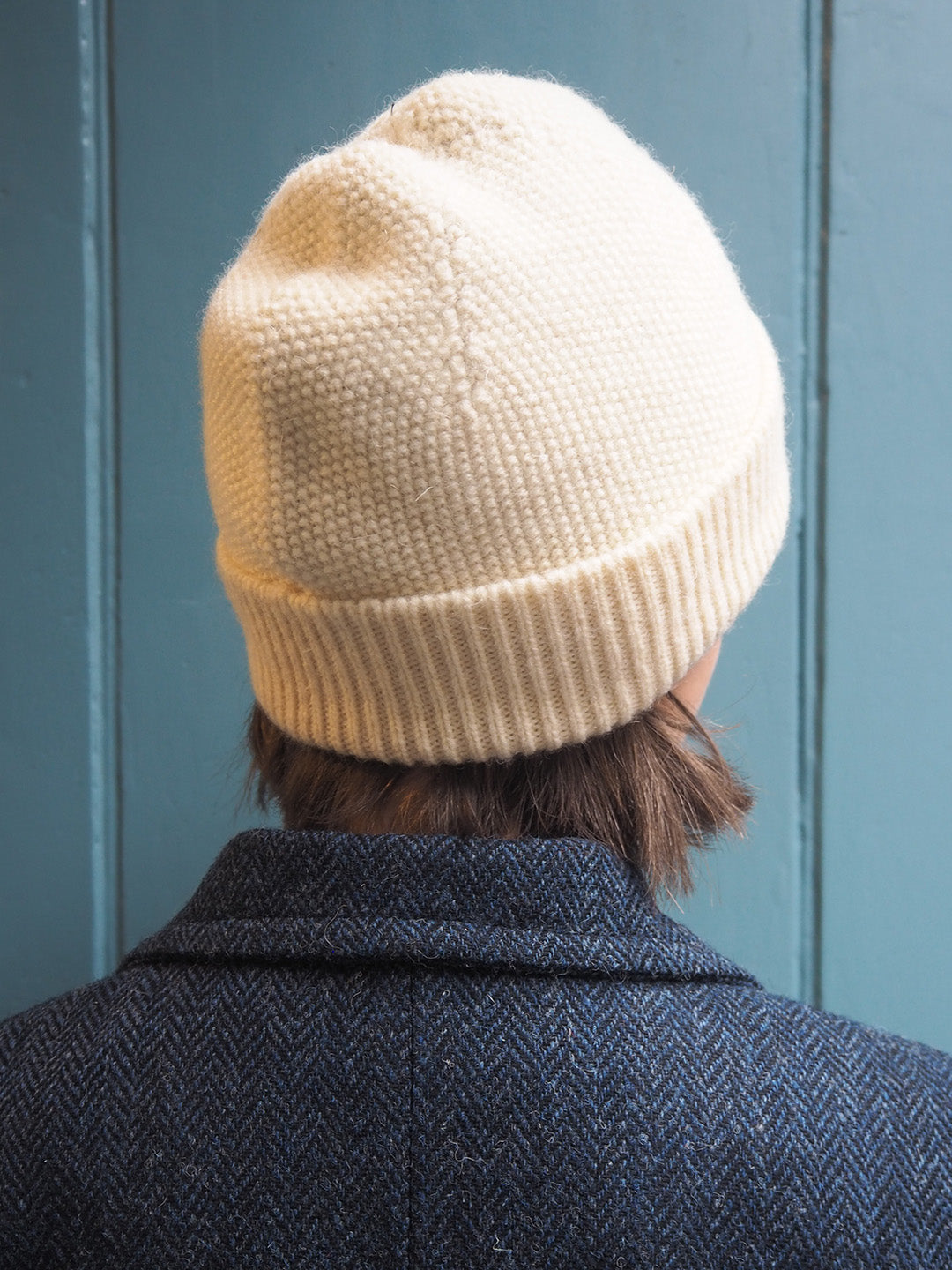 Cuillin hat in undyed natural white British wool, shown on model wearing Harris Tweed coat.