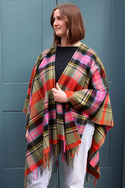 The Bruce of Kinnaird tartan serape features a bold check in an eye catching combination of vivid orange and pink, sage green and black with accents of yellow and blue.