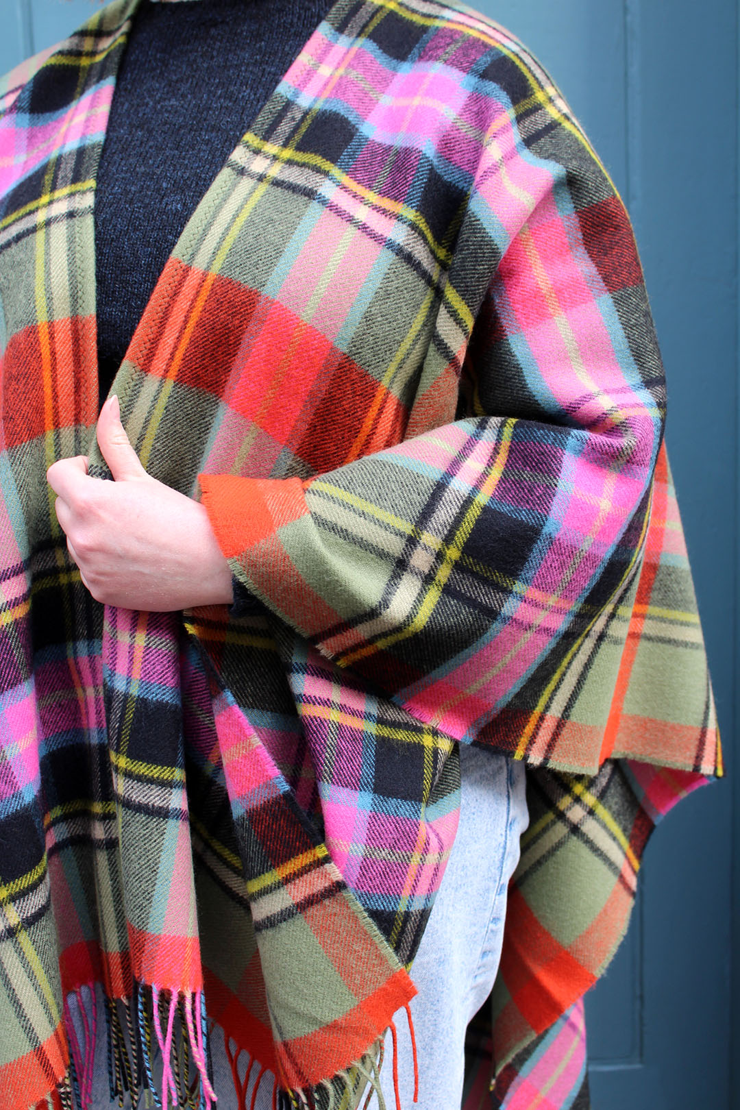 The Bruce of Kinnaird tartan serape features a bold check in an eye catching combination of vivid orange and pink, sage green and black with accents of yellow and blue.