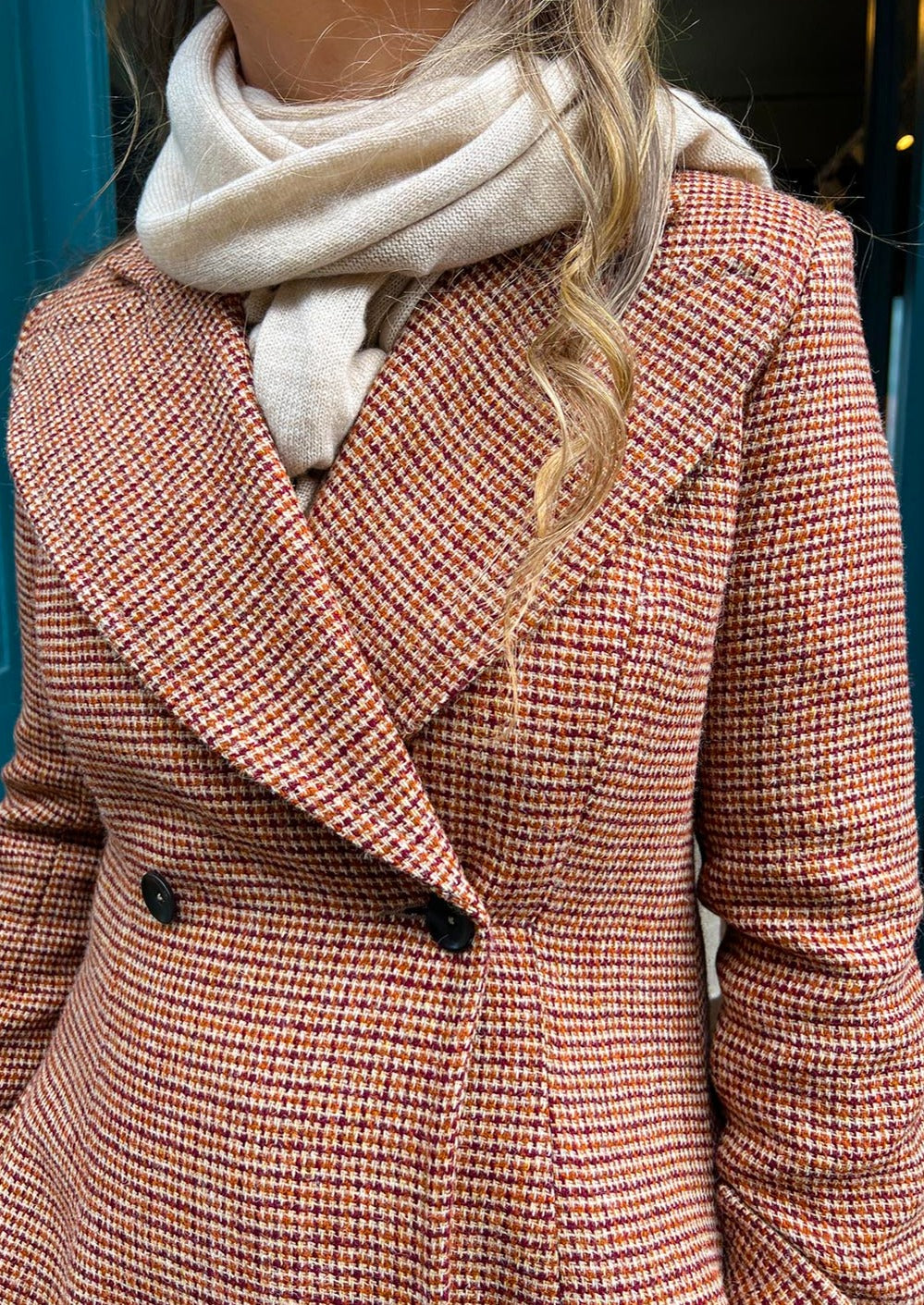 Harris Tweed ladies coat in a rust check, shown on model wearing a beige cashmere scarf.