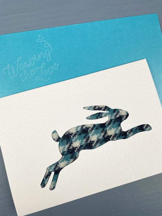 Handmade greetings card by Weaving the Love featuring leaping mountain hare in teal and navy Harris Tweed.