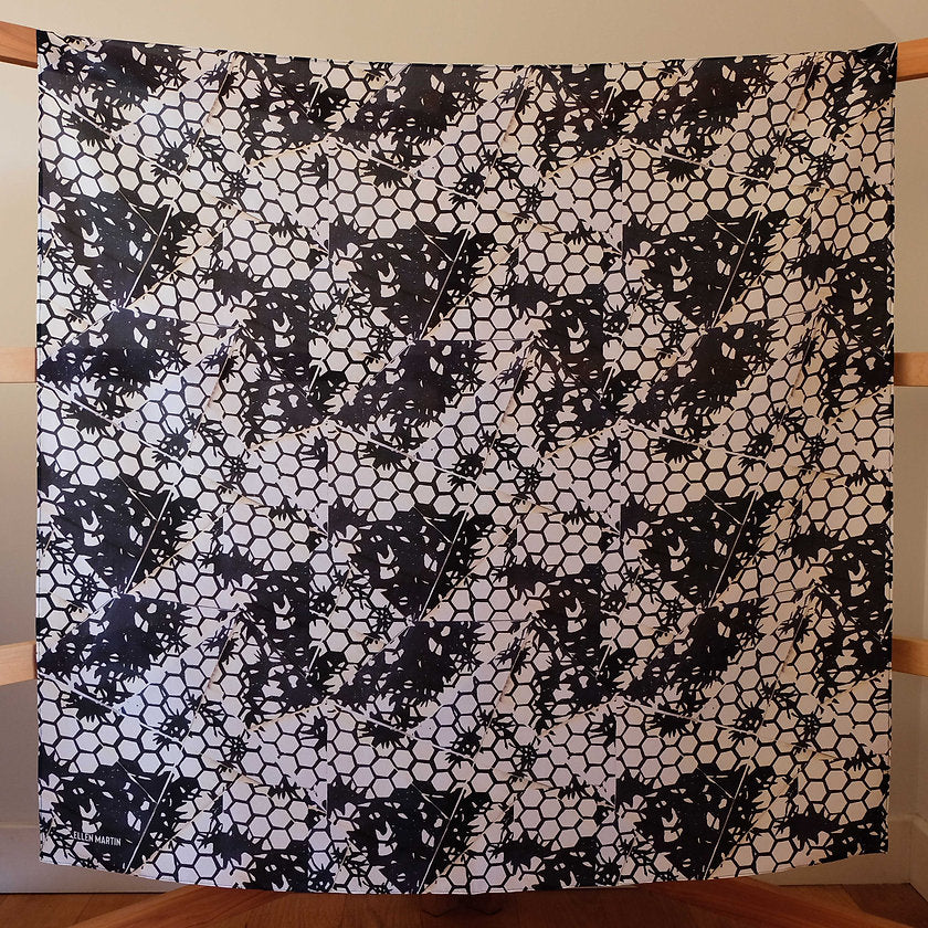 Large square silk scarf in a dark navy and cream hexagonal repeat pattern, shown hanging on wooden frame.