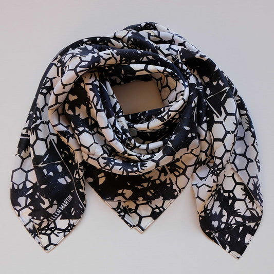 Large square silk scarf in a dark navy and cream hexagonal repeat pattern, shown draped against plain background.