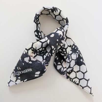 Small square silk scarf in a dark navy and cream hexagonal repeat pattern, shown tied in bow against plain background.