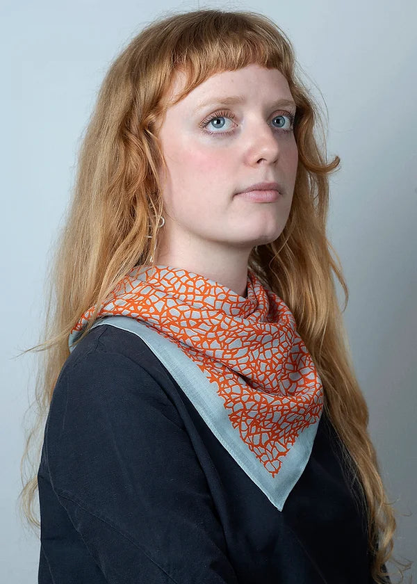 Wool and silk blend square scarf featuring intricate repeat pattern in pale blue and orange.