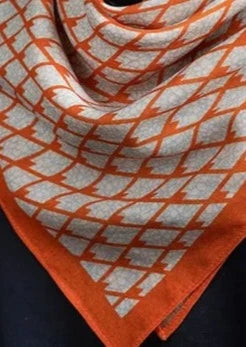 Wool and silk blend square silk scarf featuring an intricate pattern in pale blue and orange on an ivory background, shown on model.